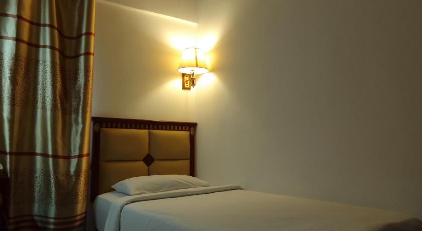 a bed in a room with a lamp on top of it, OYO 90464 Borneo Suites Hotel in Kota Kinabalu