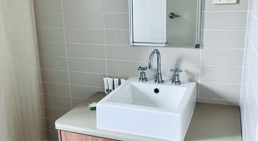 a white sink sitting under a mirror in a bathroom, The Astor Hotel Motel in Goulburn