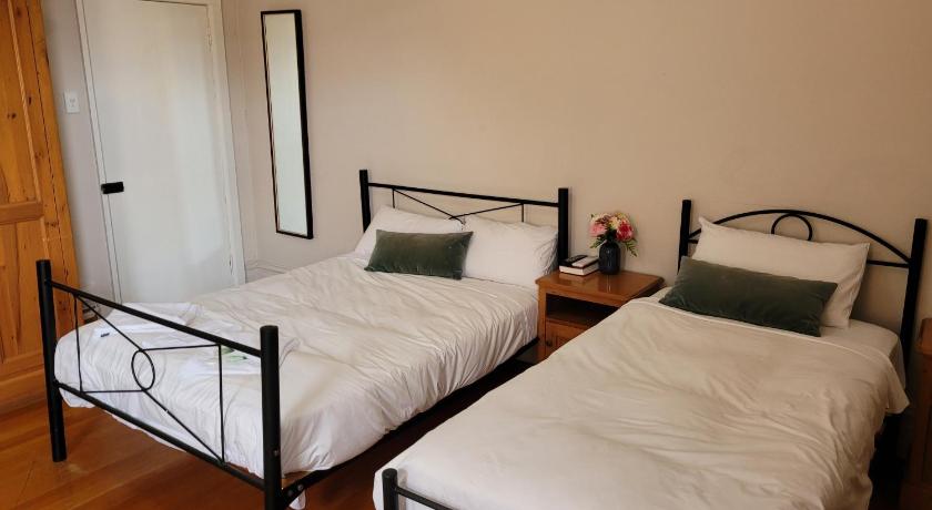 two beds in a room with a wooden floor, Burwood Bed and Breakfast in Sydney