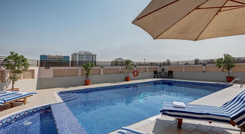 a swimming pool with a pool table, chairs and umbrellas, Radiance Premium Suites in Dubai