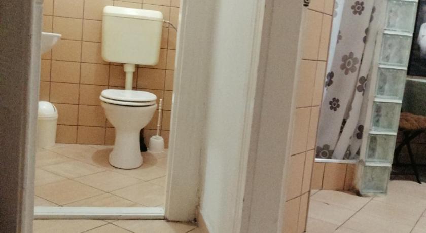 a white toilet sitting in a bathroom next to a sink, Nepkerti Vendeghaz in Miskolc