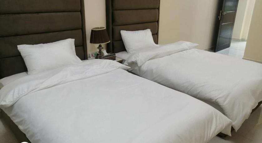 two beds in a hotel room with white comforters, Al Rawda Apartments -Ajman in Ajman