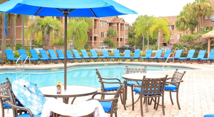 a patio area with tables, chairs and umbrellas, Polynesian Isles Resort in Orlando (FL)