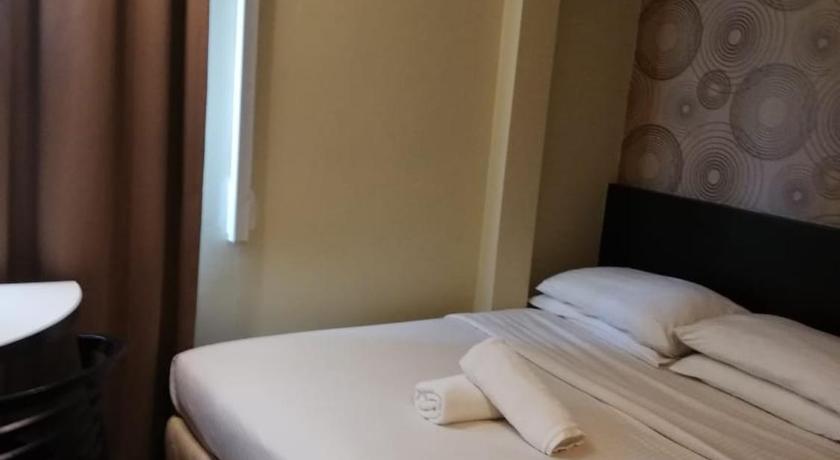 a hotel room with a white bed and a white comforter, Regalo Hotel Kota Laksamana in Malacca