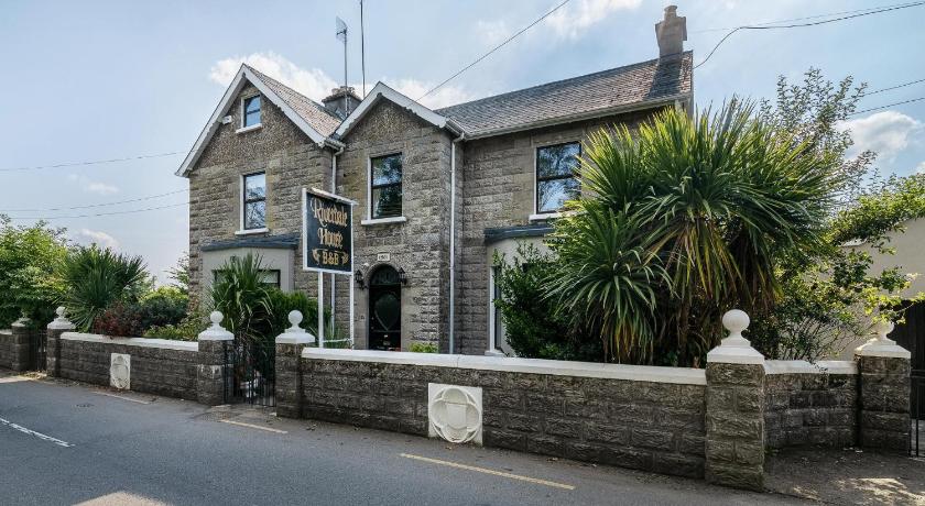 a white house with a stone wall and a stone clock tower, Riverdale House B&B in Athlone