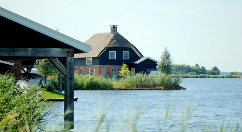 a house that has a boat in the water, Waterresort Bodelaeke Giethoorn in Giethoorn