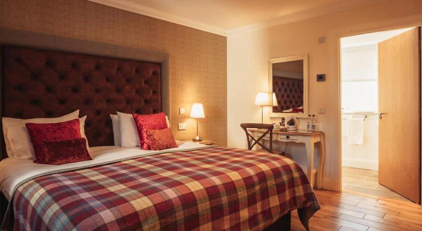 a hotel room with a bed and a dresser, The Bowmore Lodge in Bowmore