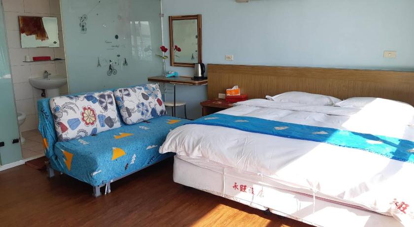a bed in a room with a white bedspread, Yong Wong Hostel in Kenting