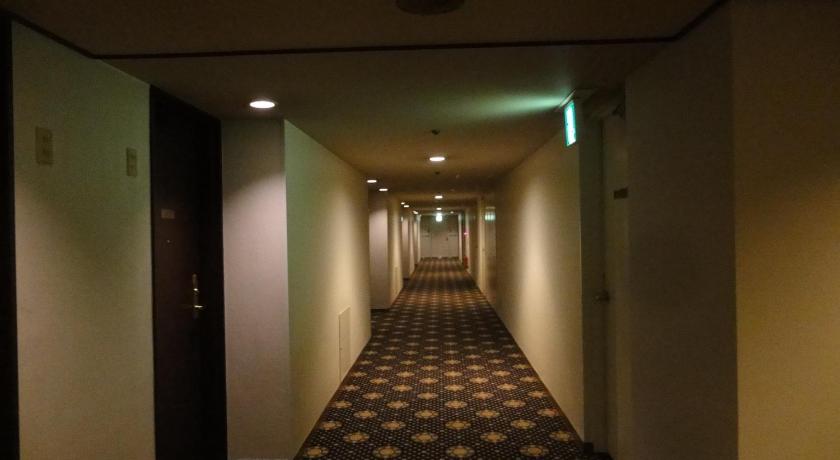 a hallway with a stairway leading to a room with a door, Mito Keisei Hotel in Mito