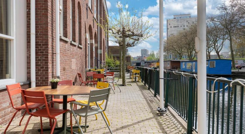 a patio area with chairs, tables, and umbrellas, Stayokay Hostel Den Haag in The Hague