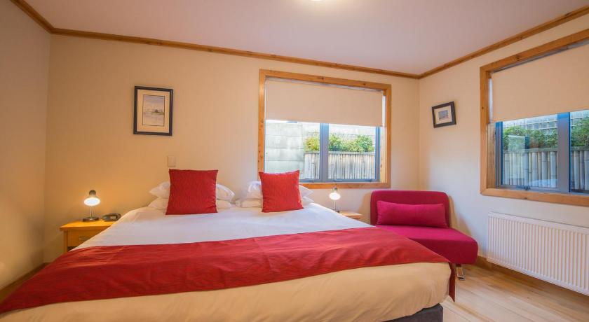 a bedroom with a large bed and a large window, Coronation Lodge in Queenstown