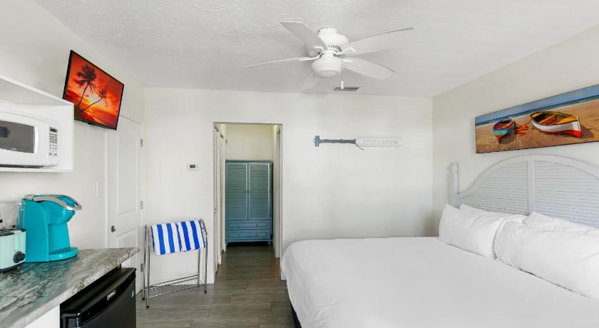 a bedroom with a white bed and white walls, Tropical Breeze Resort in Siesta Key (FL)