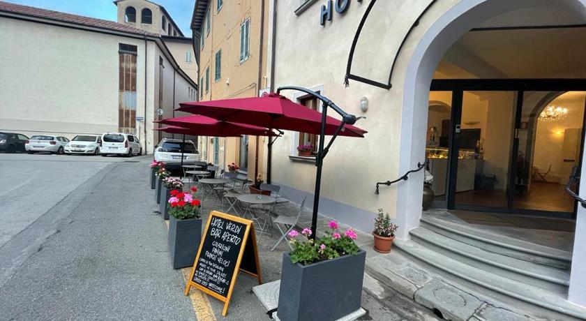 a red umbrella sitting on a sidewalk next to a building, Hotel Verdi in Pisa