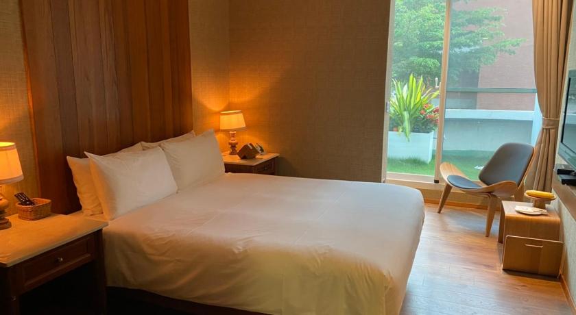 a hotel room with a bed, chair, and a window, Sizihwan Sunset Beach Resort in Kaohsiung