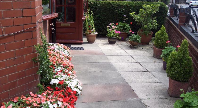 a garden with flowers and plants in front of a brick building, Butterfly Guest House in Manchester