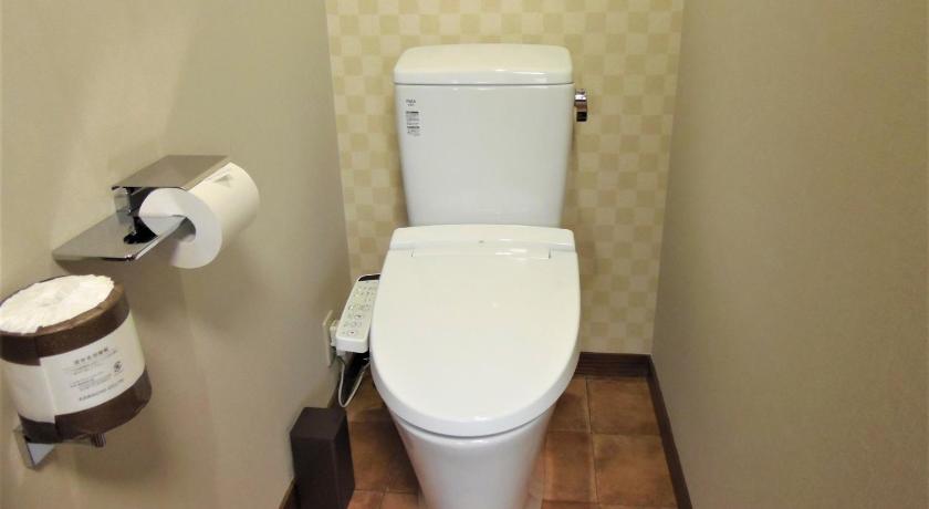 a white toilet sitting next to a toilet paper dispenser, Sanso Tanaka in Yufu