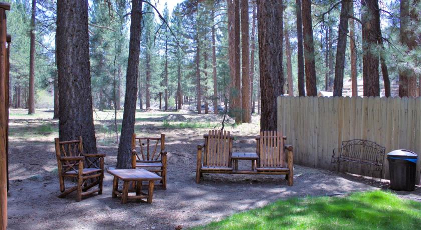 a wooden bench sitting in the middle of a wooded area, Goldmine Lodge in Big Bear Lake (CA)