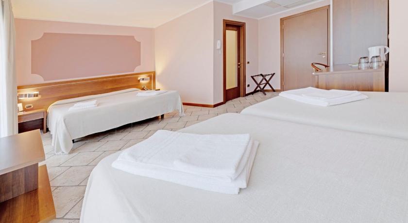 a hotel room with two beds and a television, Hotel Grotto Bagat in Lavena Ponte Tresa