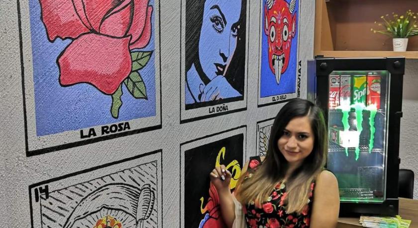 a woman standing next to a wall with a painting on it, Posada Vs4 Aeropuerto in Mexico City