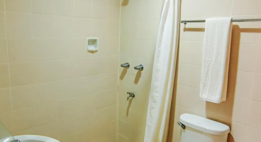 a white toilet sitting next to a bath tub in a bathroom, Rajah Park Hotel in Cebu
