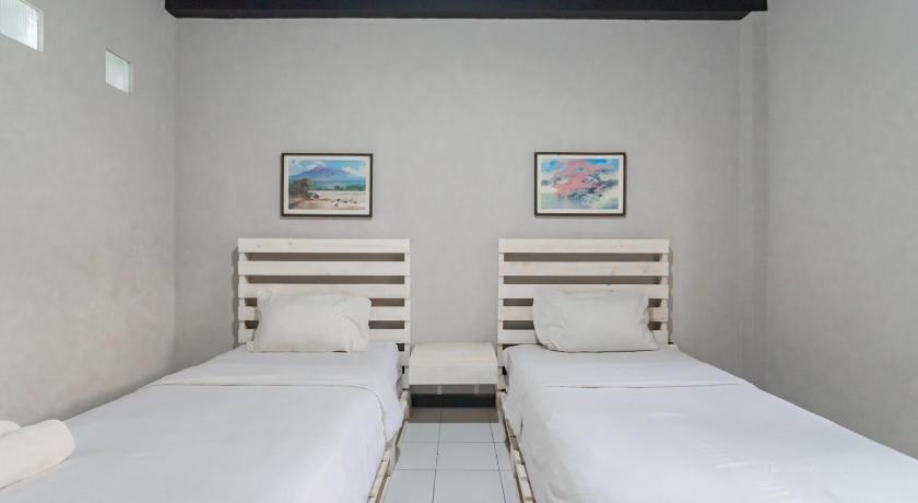 a row of white beds in a room, RedDoorz @ Home 33 Bandung in Bandung