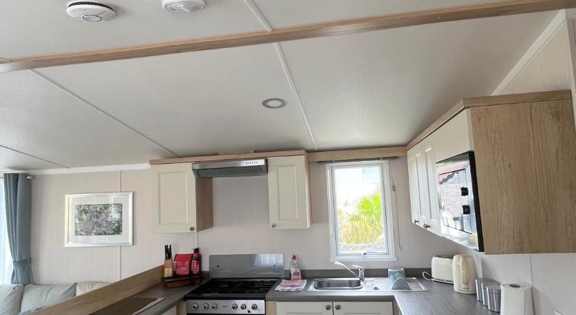 a kitchen with a stove top oven and a sink, Sunnycott Caravan Park in Isle of Wight