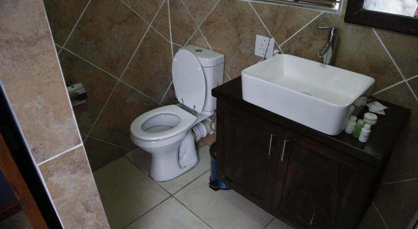 a white toilet sitting next to a sink in a bathroom, Travetel OR Tambo Airport in Johannesburg