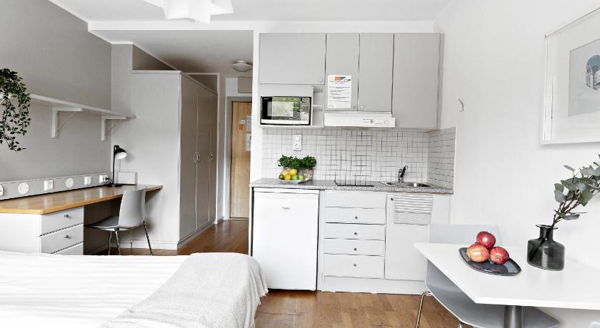a white kitchen with a white bed and white cabinets, Forenom Aparthotel Stockholm Alvik in Stockholm