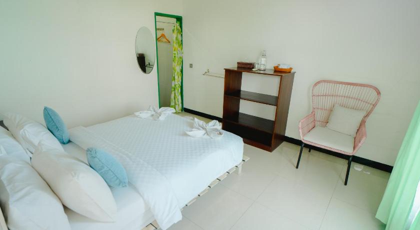 a bedroom with a bed, chair, mirror and a dresser, Green Hill Boutique Hotel in Labuan Bajo