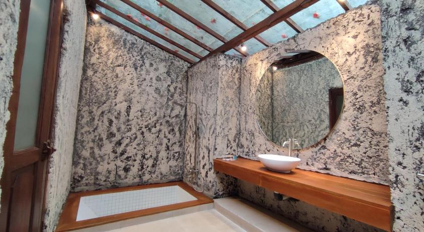 a bathroom with a large mirror and a sink, Imah Seniman Hotel in Bandung