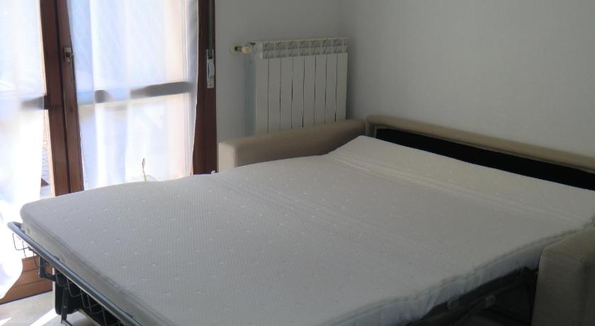 a white bed sitting in a room next to a window, Residence Daytona in Caorle