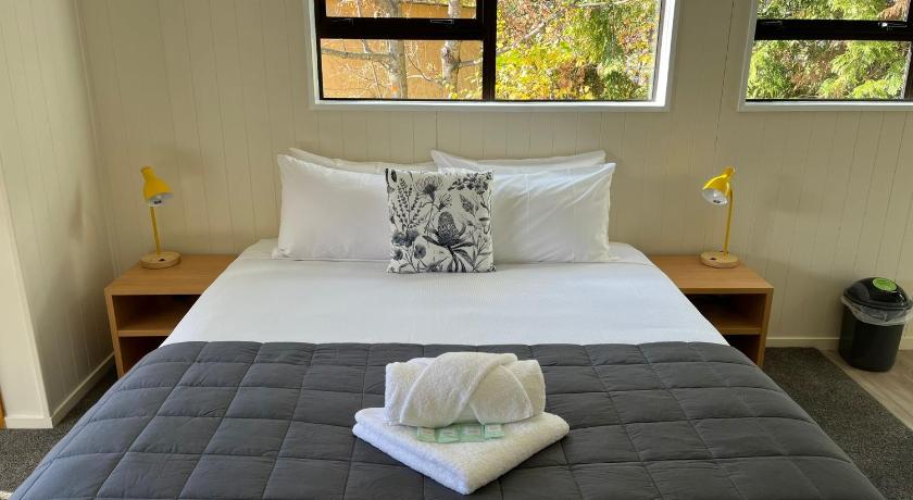 a bed with a white blanket and pillows on top of it, Omarama TOP10 Holiday Park in Omarama