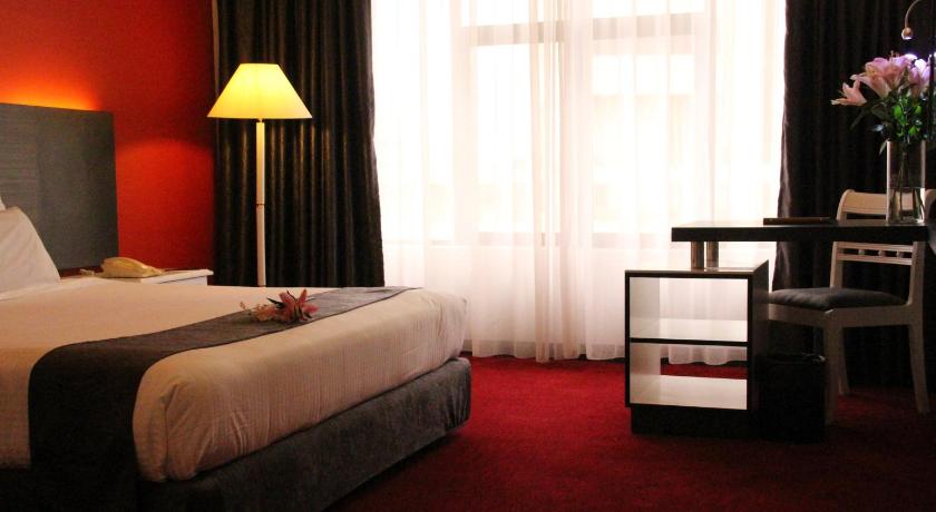 a hotel room with a bed, chair, lamp and window, Grand Riverview Hotel in Kota Bharu