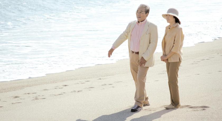 a man and a woman walking on the beach, Luxze Hitotsuba Cottage Himuka in Miyazaki