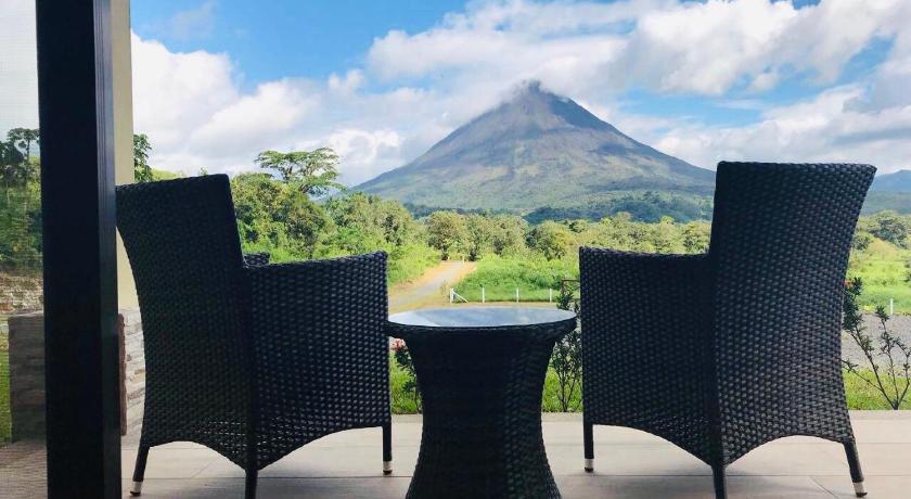 two chairs and a table in front of a forest, Arenal Roca Suites in La Fortuna