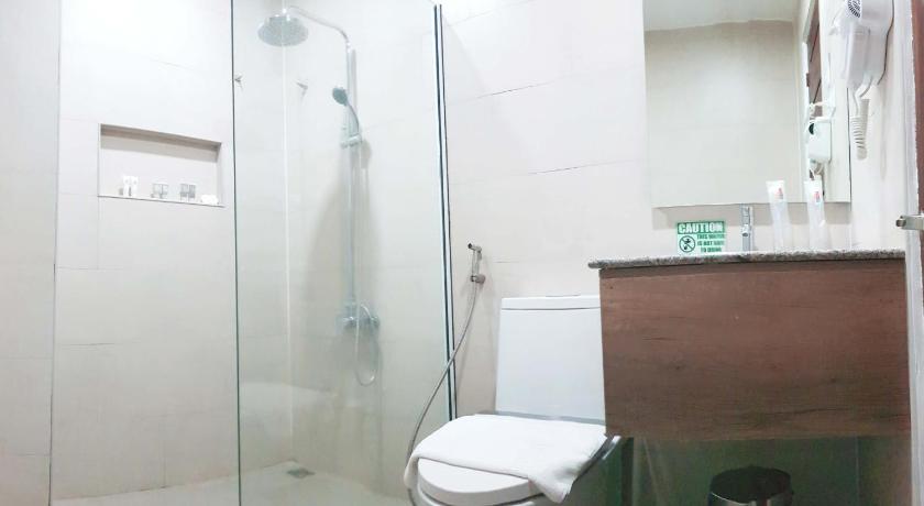 a white toilet sitting next to a shower in a bathroom, Carlosta Hotel in Ormoc