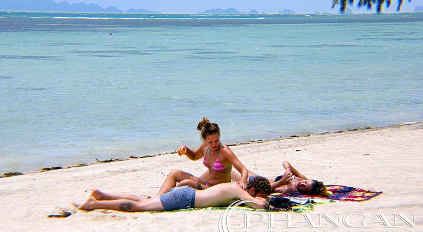 a woman sitting on a beach next to a body of water, Phangan Beach Resort in Ko Pha-ngan