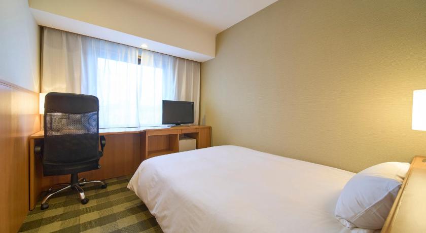 a hotel room with a bed, chair, desk and television, Hotel Granvia Wakayama in Wakayama