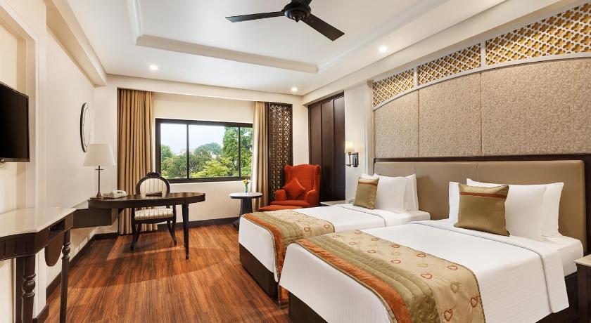 a hotel room with a bed and a chair, La Place Sarovar Portico Lucknow in Lucknow