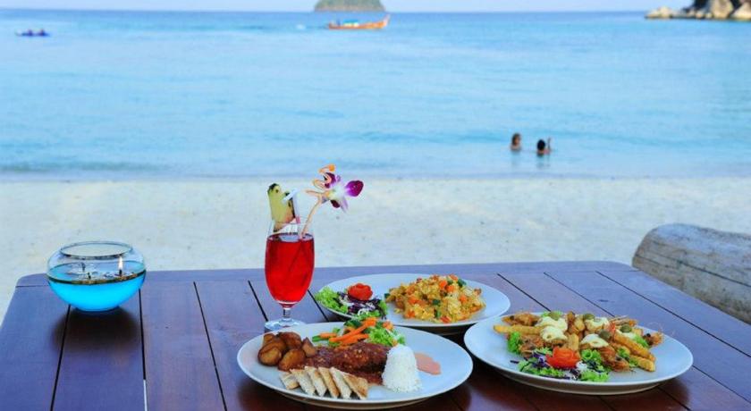 a table topped with plates of food and drinks, Anda Lipe Resort in Ko Lipe