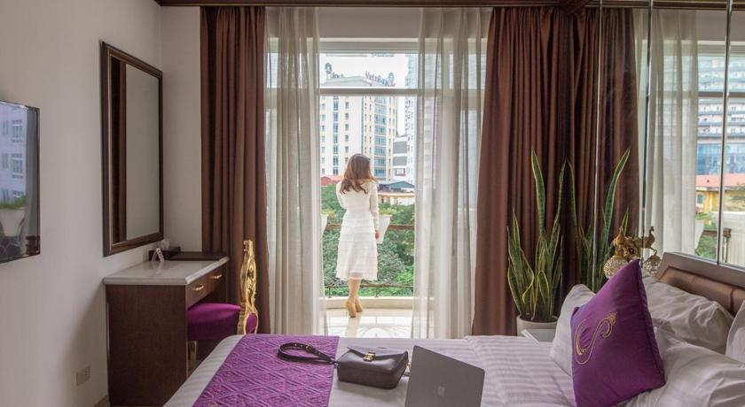 a woman is using a laptop on a bed, Suji Hotel in Hanoi