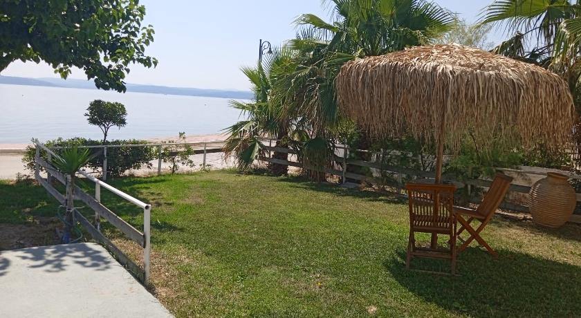 a picnic table in a grassy area next to a beach, Evoikos beach & resort in Livanatai