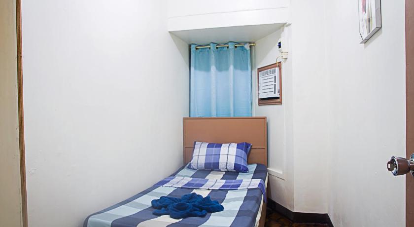 a bed in a room with a blue wall, Providence Travellers Inn & Spa in Bohol