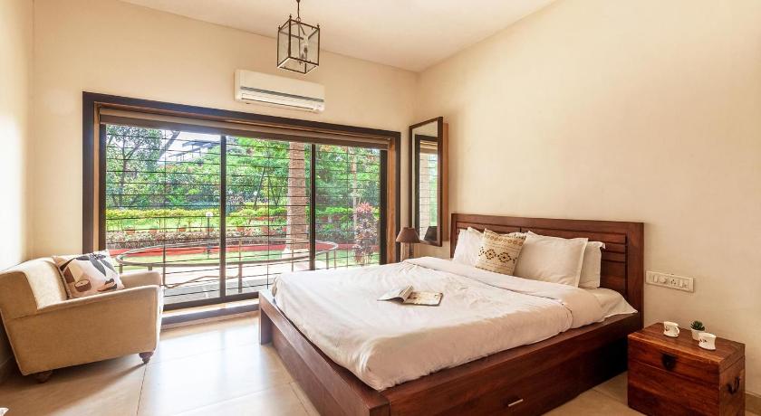 a bedroom with a large bed and a large window, StayVista at Valencia in Lonavala