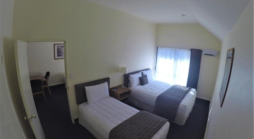 a hotel room with two beds and a television, The Peaks Motor Inn in Ohakune