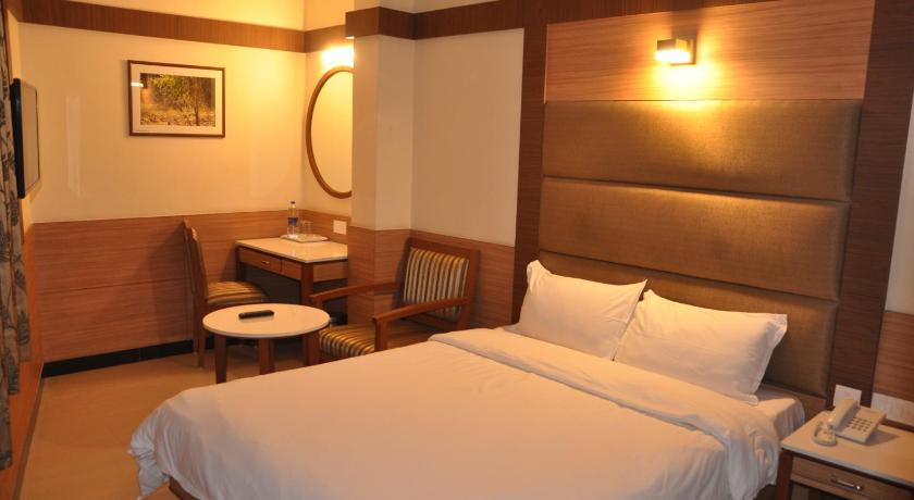 a hotel room with two beds and a television, Hotel Sms Grand Inn in Vellore