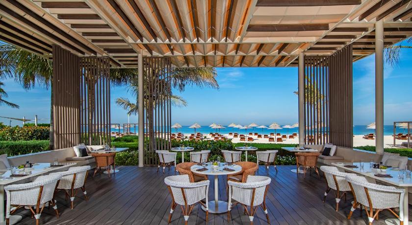 a dining room table with chairs and umbrellas, The Oberoi Beach Resort, Al Zorah in Ajman