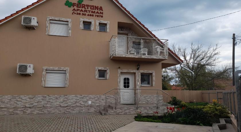 a large brick building with a clock on the front of it, Fortuna Apartman in Gyula