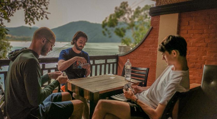 people sitting around a wooden table, Hotel Forest Lake Backpackers' Hostel in Pokhara