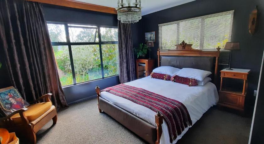 a bedroom with a large bed and a large window, Waitapu Springs B&B in Golden Bay